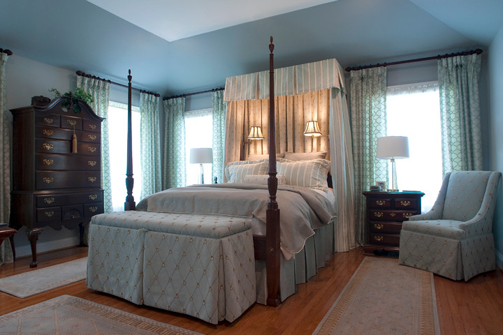 Inspiration pour une chambre parentale traditionnelle de taille moyenne avec un mur bleu, un sol en bois brun, aucune cheminée et un sol marron.