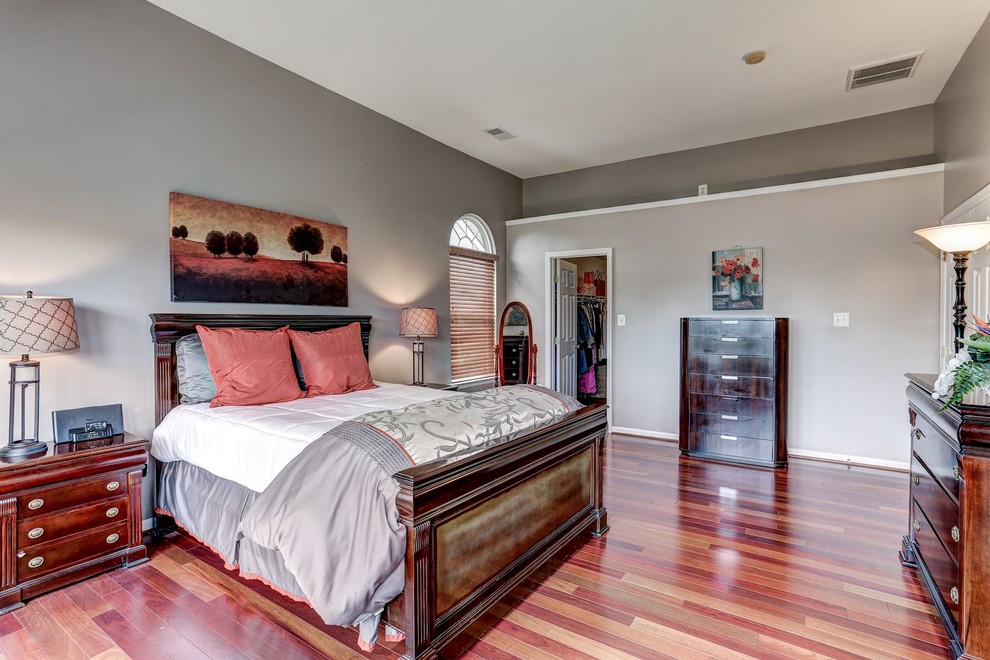 Cette image montre une grande chambre parentale design avec un mur gris et un sol en bois brun.