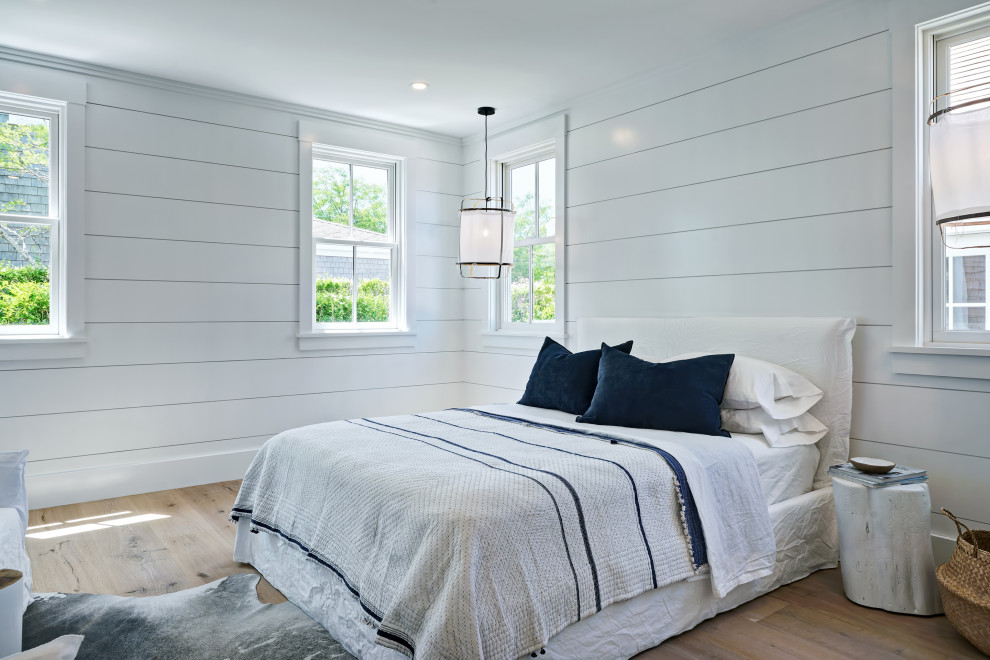 Maritimes Schlafzimmer ohne Kamin mit weißer Wandfarbe und hellem Holzboden in Sonstige