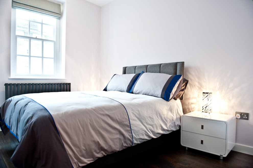 На фото: хозяйская спальня среднего размера в стиле модернизм с белыми стенами и темным паркетным полом с