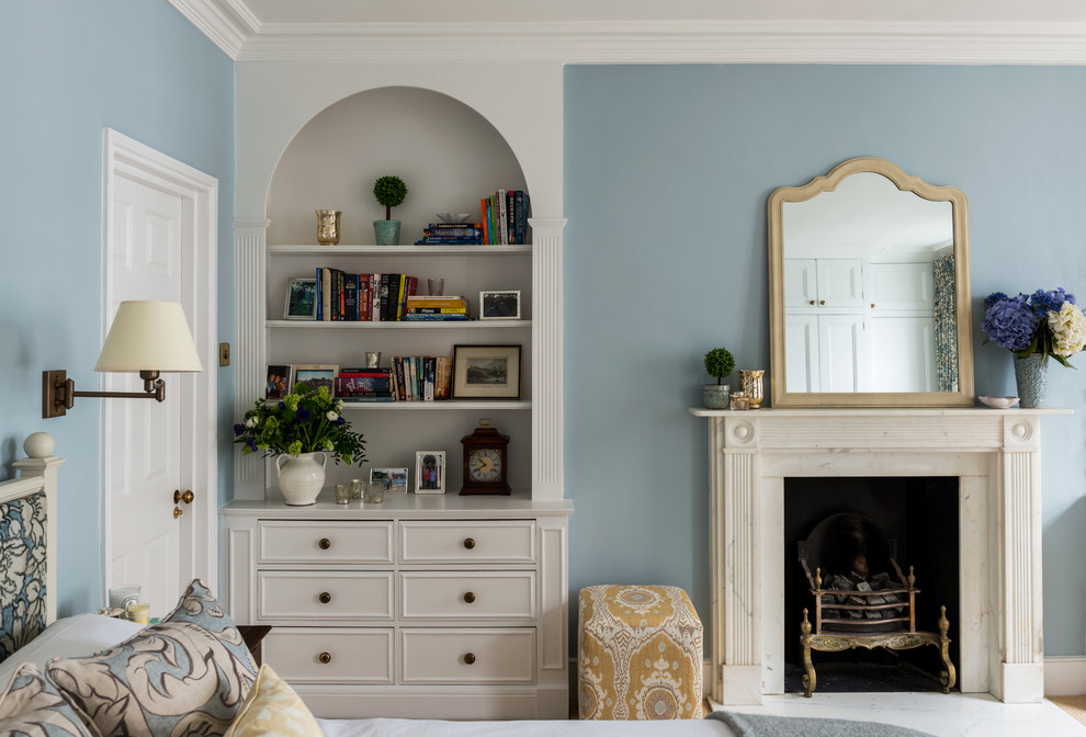 Cette photo montre une chambre chic de taille moyenne avec un mur bleu, une cheminée standard et un manteau de cheminée en pierre.