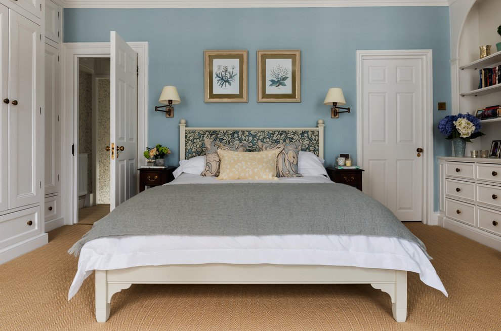На фото: хозяйская спальня среднего размера в стиле неоклассика (современная классика) с синими стенами, ковровым покрытием, стандартным камином и фасадом камина из камня