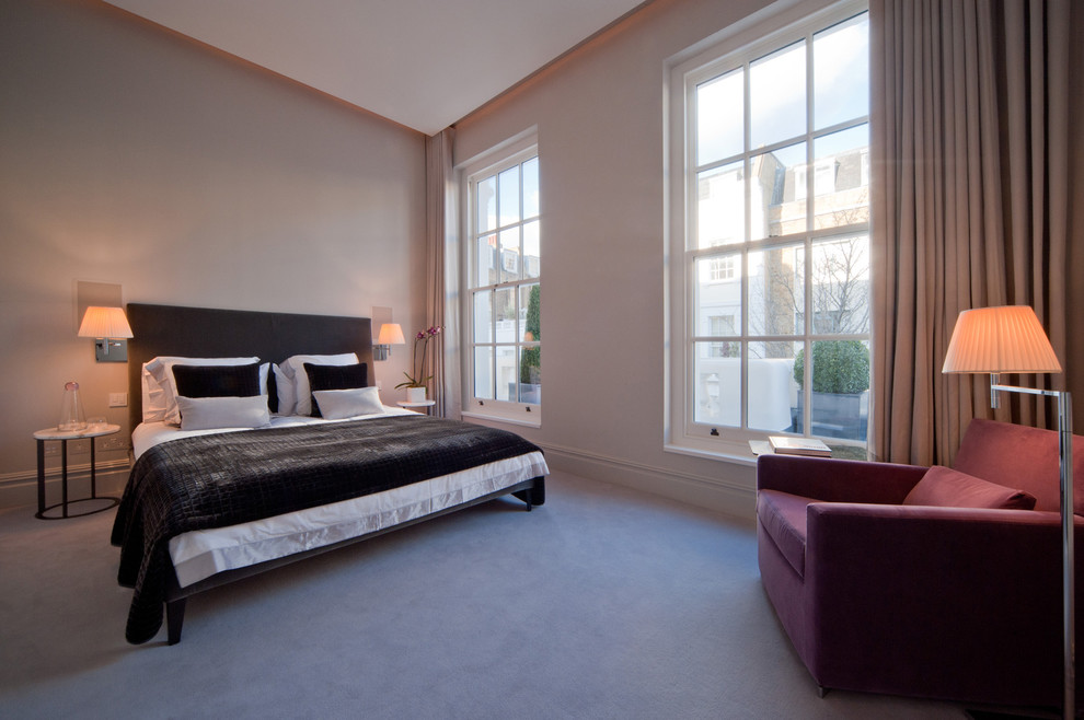 This is an example of a contemporary master bedroom in London with beige walls and carpet.