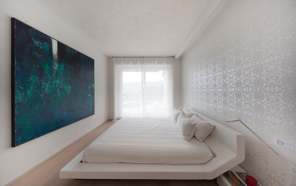Modelo de dormitorio principal contemporáneo con paredes blancas y suelo de madera clara