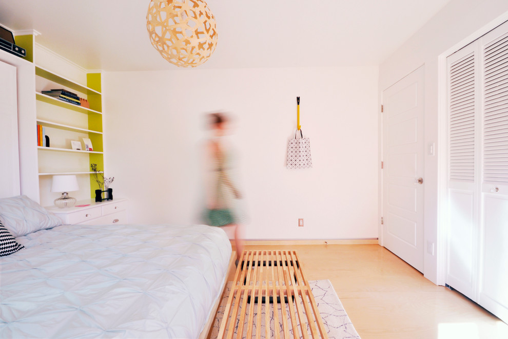 Ispirazione per una camera da letto design con pavimento in compensato e pareti bianche