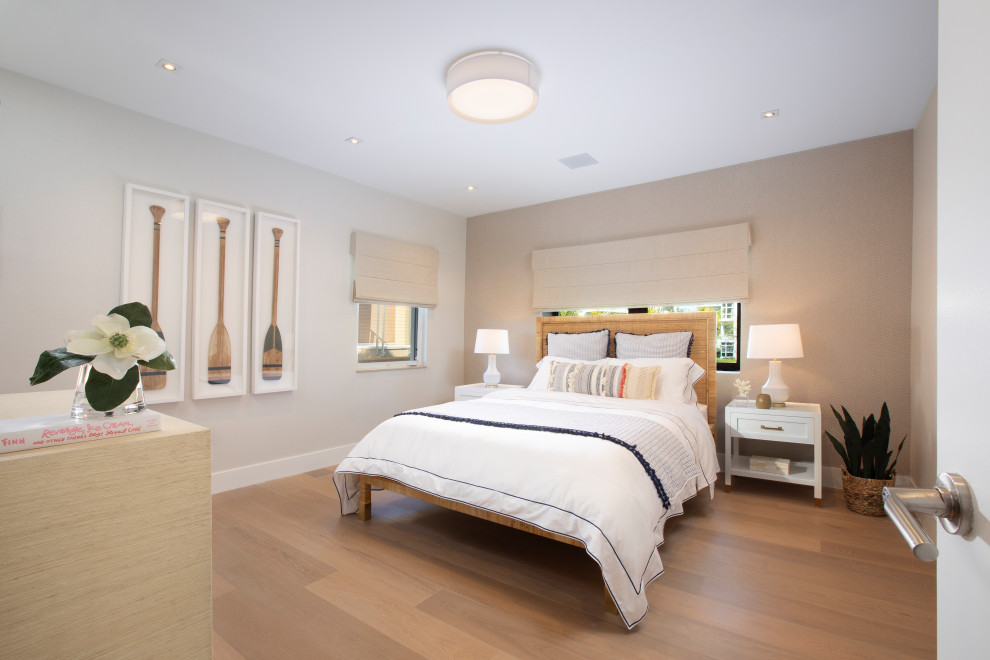 Diseño de habitación de invitados costera grande sin chimenea con paredes beige, suelo de madera en tonos medios y suelo marrón