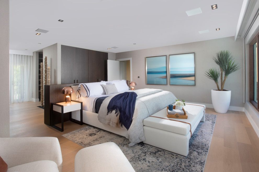 Imagen de dormitorio principal costero grande sin chimenea con paredes grises, suelo de madera en tonos medios y suelo marrón