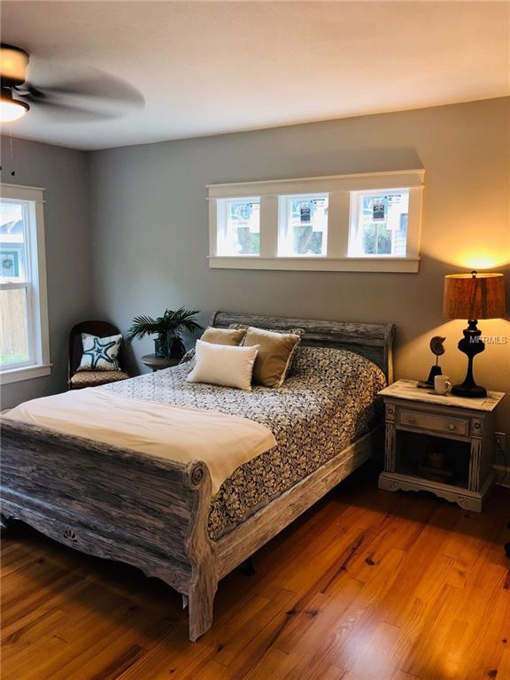 Mittelgroßes Mid-Century Hauptschlafzimmer ohne Kamin mit grauer Wandfarbe, braunem Holzboden und braunem Boden in Tampa