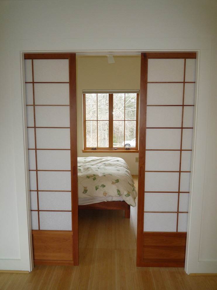 На фото: гостевая спальня (комната для гостей) в стиле неоклассика (современная классика) с белыми стенами и полом из бамбука