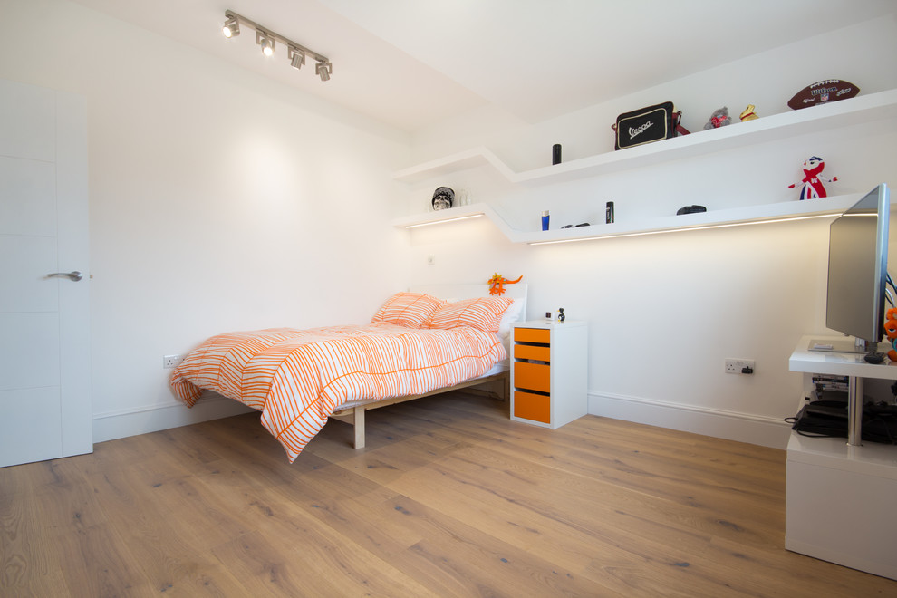 This is an example of a medium sized modern guest bedroom in London with white walls, medium hardwood flooring and no fireplace.