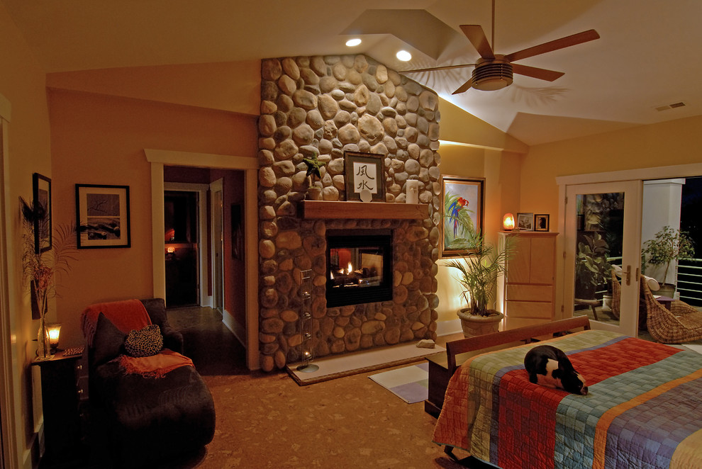 Foto de dormitorio principal ecléctico grande con marco de chimenea de piedra, paredes beige, suelo de corcho, chimenea de doble cara y suelo beige