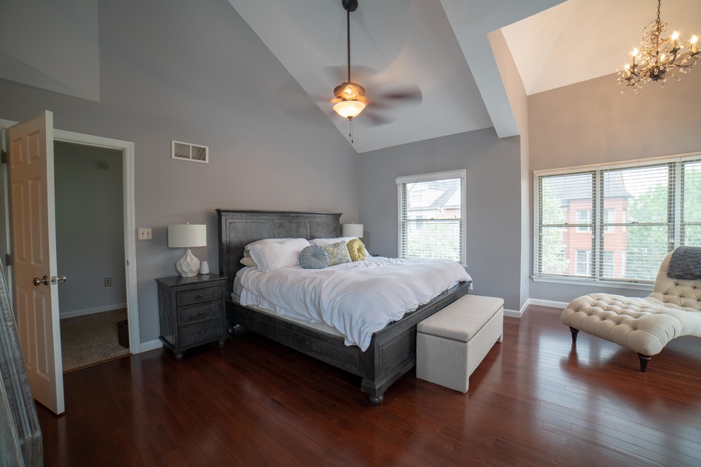 Diseño de dormitorio principal de tamaño medio sin chimenea con paredes grises, suelo de madera oscura y suelo rojo