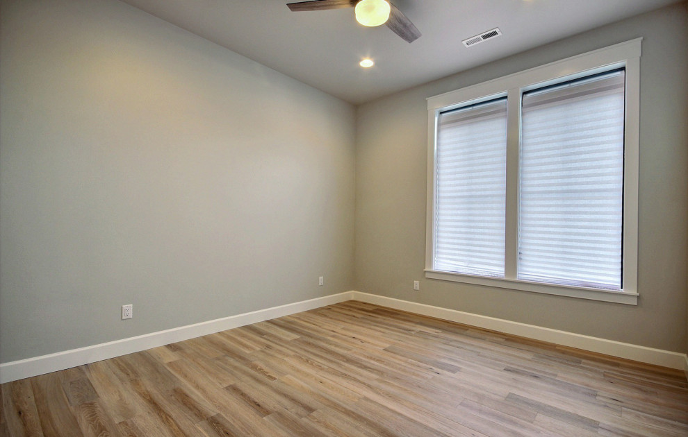 Immagine di un'ampia camera degli ospiti country con pareti beige, parquet chiaro e pavimento marrone