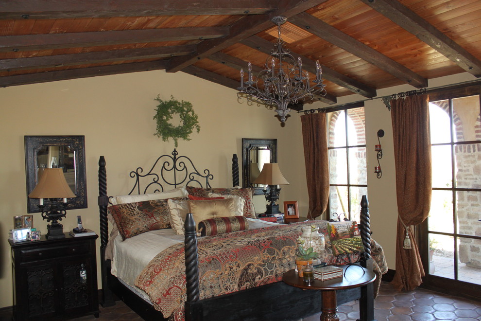 Стильный дизайн: большая хозяйская спальня в средиземноморском стиле с бежевыми стенами, полом из терракотовой плитки и коричневым полом - последний тренд