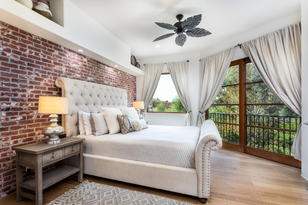 Immagine di una camera da letto mediterranea con pareti bianche, parquet chiaro, pavimento beige e pareti in mattoni