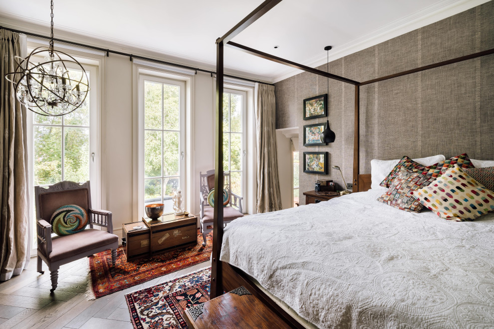 Imagen de dormitorio principal bohemio con paredes grises, suelo de madera en tonos medios, suelo marrón y papel pintado