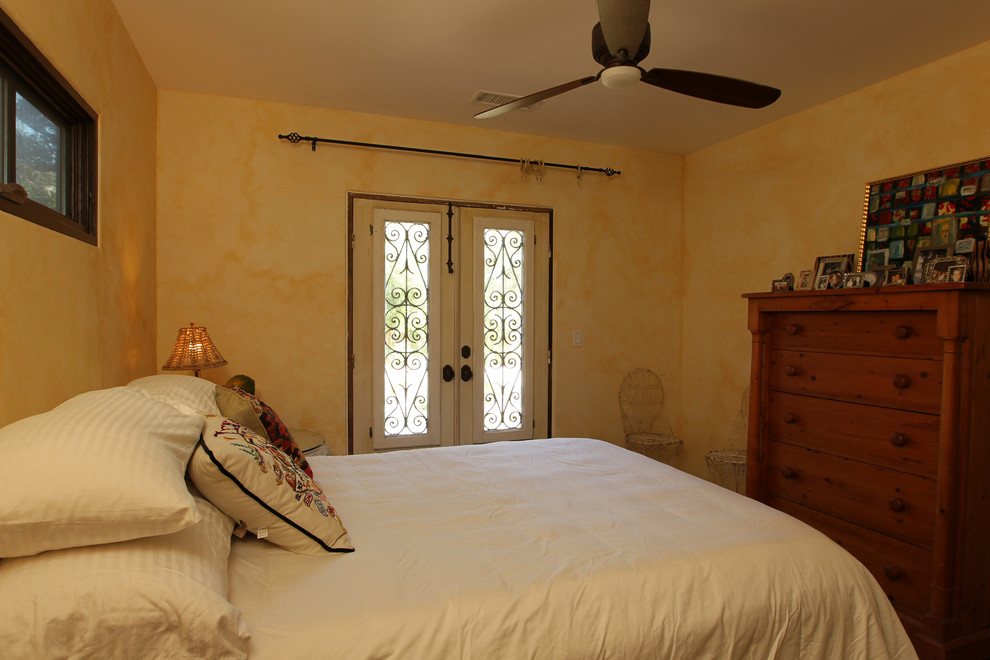 Diseño de habitación de invitados mediterránea pequeña sin chimenea con suelo de madera oscura, paredes amarillas y suelo marrón