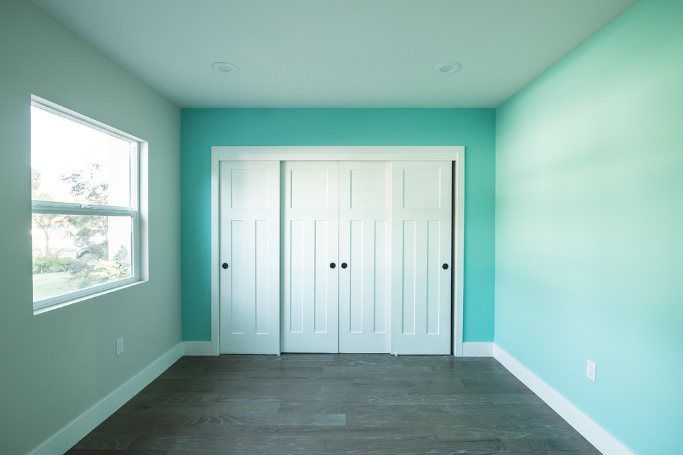 Modelo de habitación de invitados clásica renovada de tamaño medio sin chimenea con paredes verdes, suelo de madera en tonos medios y suelo verde