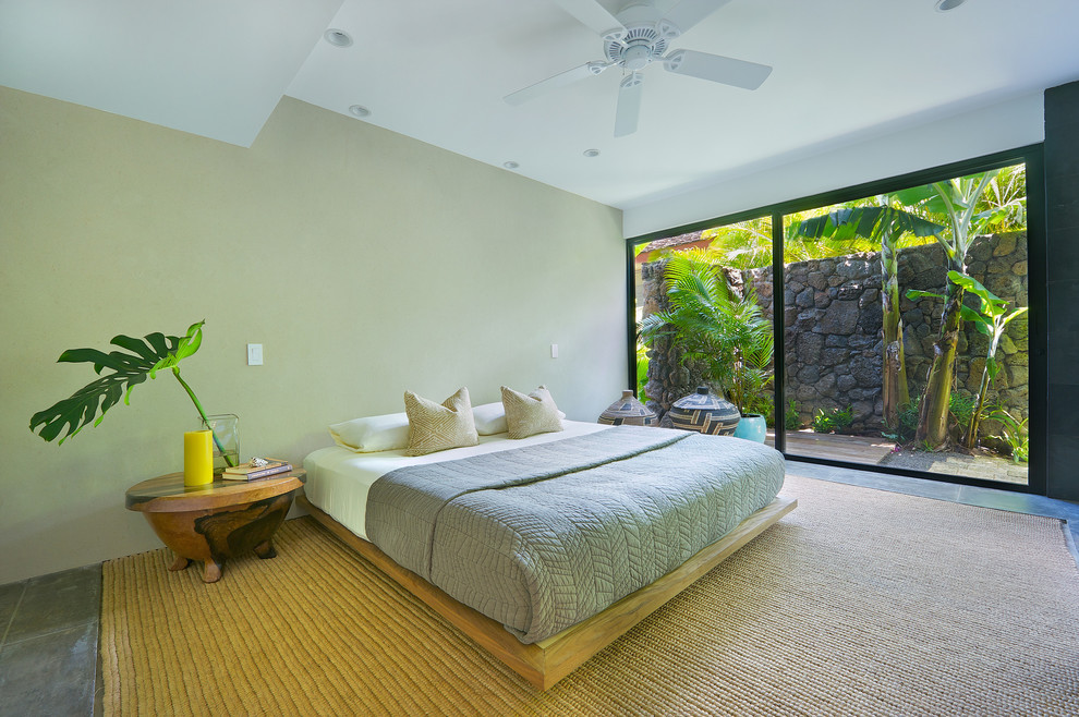 Ispirazione per una grande camera degli ospiti tropicale con pareti grigie, pavimento in cemento e pavimento beige