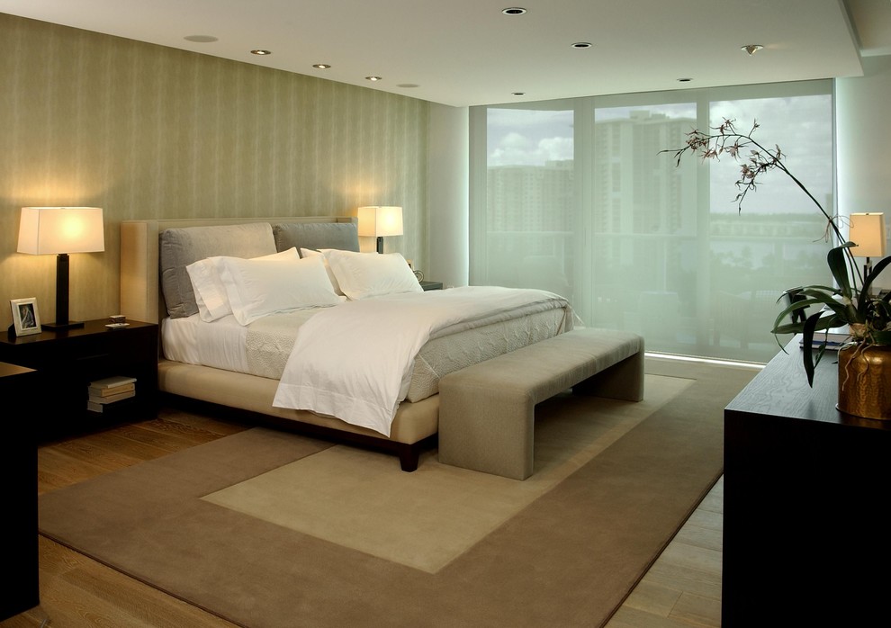 Immagine di una camera da letto design con pareti beige e parquet chiaro