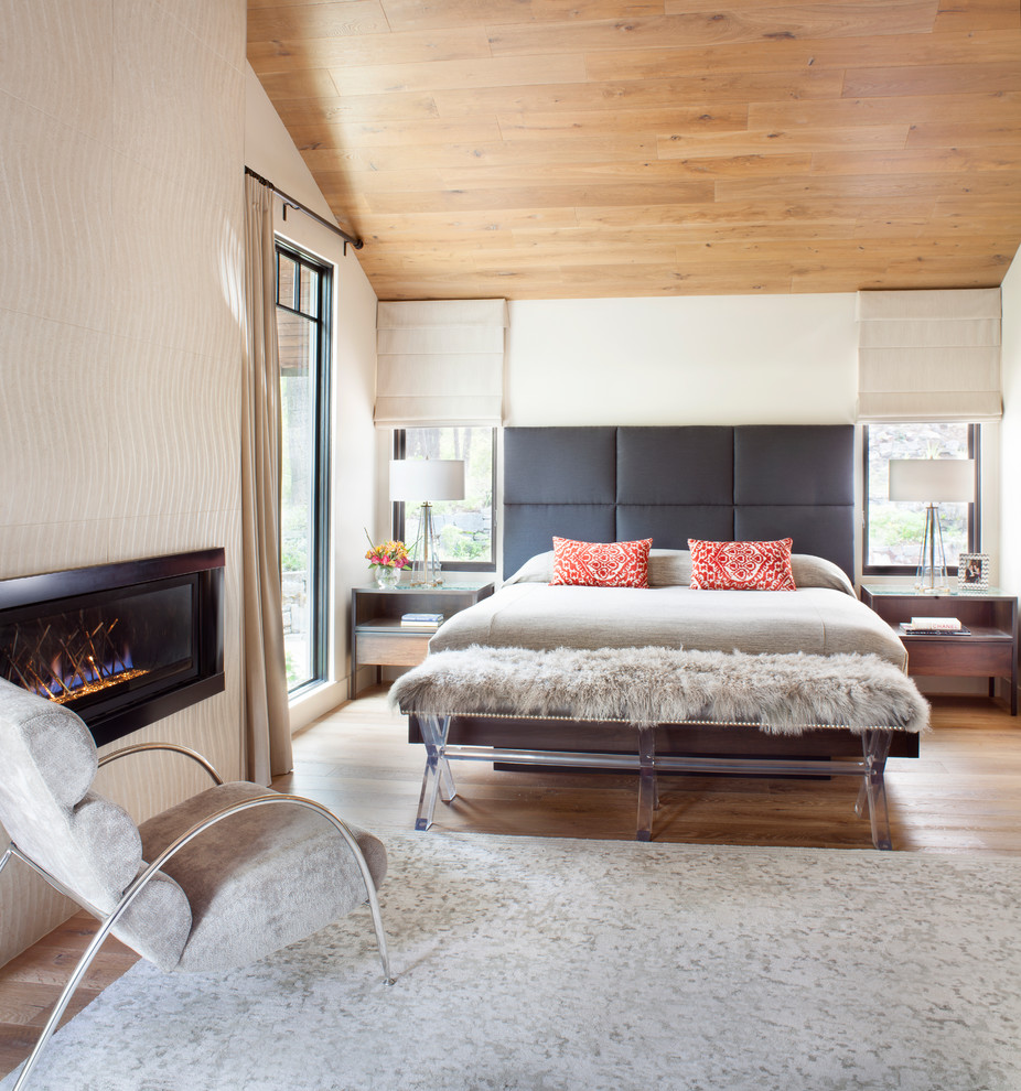 Ejemplo de dormitorio principal contemporáneo con paredes blancas, suelo de madera clara, chimenea lineal, marco de chimenea de baldosas y/o azulejos y suelo beige