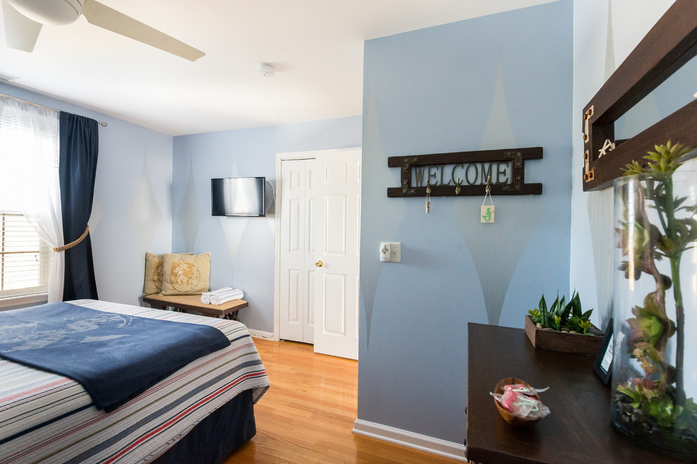 Modelo de habitación de invitados marinera de tamaño medio con paredes azules y suelo de madera clara