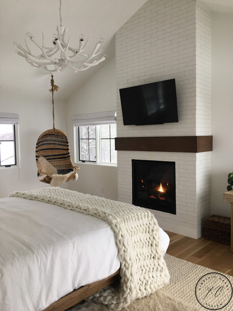 На фото: хозяйская спальня в стиле фьюжн с белыми стенами, паркетным полом среднего тона, стандартным камином, фасадом камина из плитки, коричневым полом и сводчатым потолком