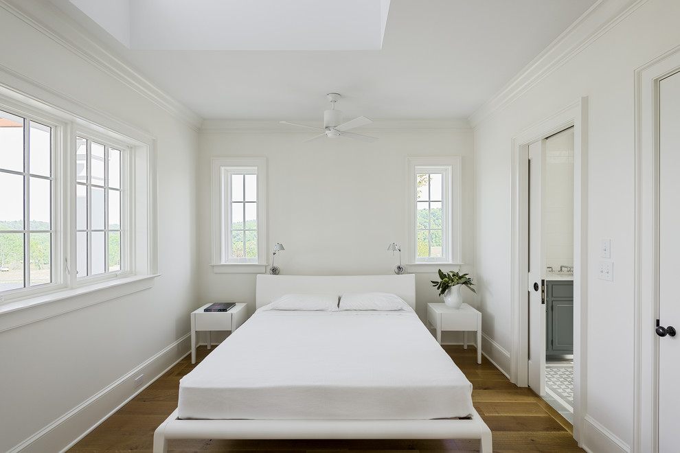 Photo of a farmhouse bedroom in New York with white walls and medium hardwood flooring.