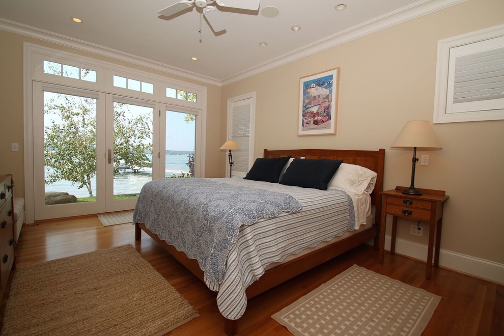 Ejemplo de habitación de invitados costera de tamaño medio sin chimenea con paredes amarillas, suelo de madera en tonos medios y suelo marrón