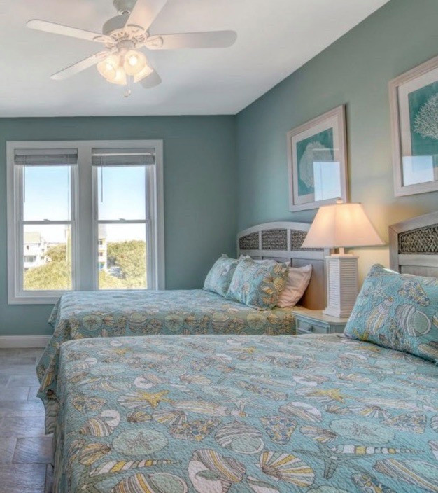 Exemple d'une grande chambre d'amis bord de mer avec un mur bleu, un sol en carrelage de céramique et un sol beige.