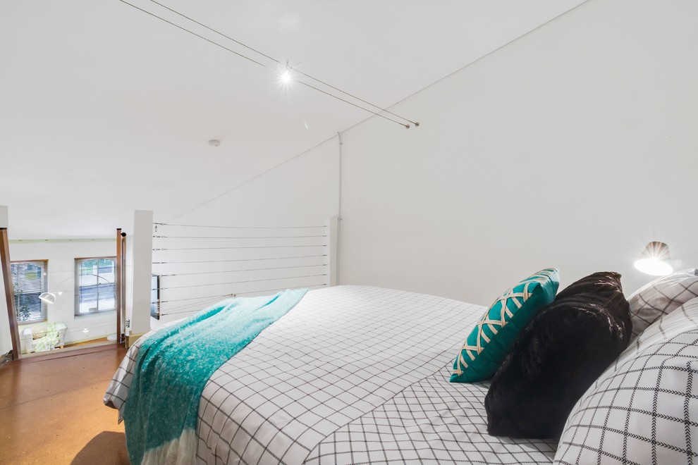 アデレードにあるインダストリアルスタイルのおしゃれなロフト寝室 (白い壁、コルクフローリング)