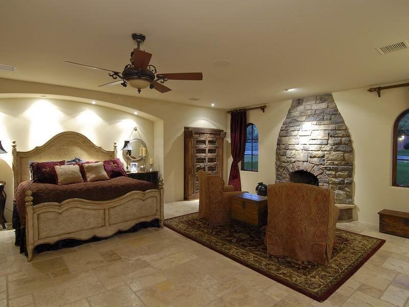 Пример оригинального дизайна: большая хозяйская спальня в средиземноморском стиле с бежевыми стенами, полом из керамической плитки, стандартным камином и фасадом камина из камня