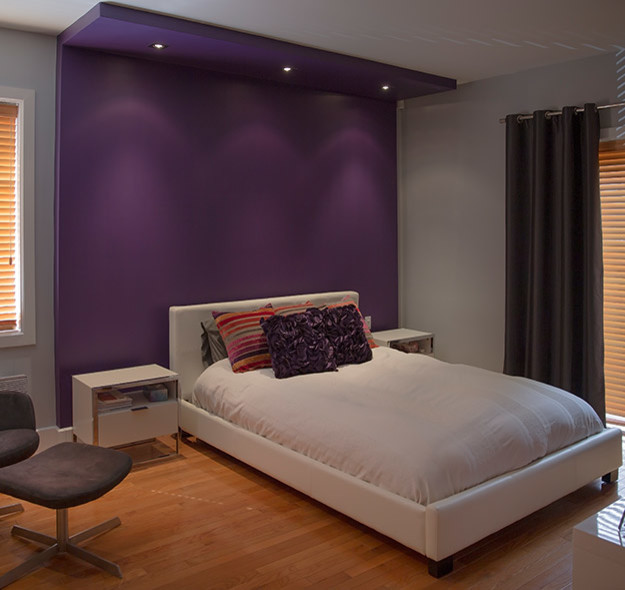 Imagen de dormitorio actual con paredes púrpuras y suelo de madera clara