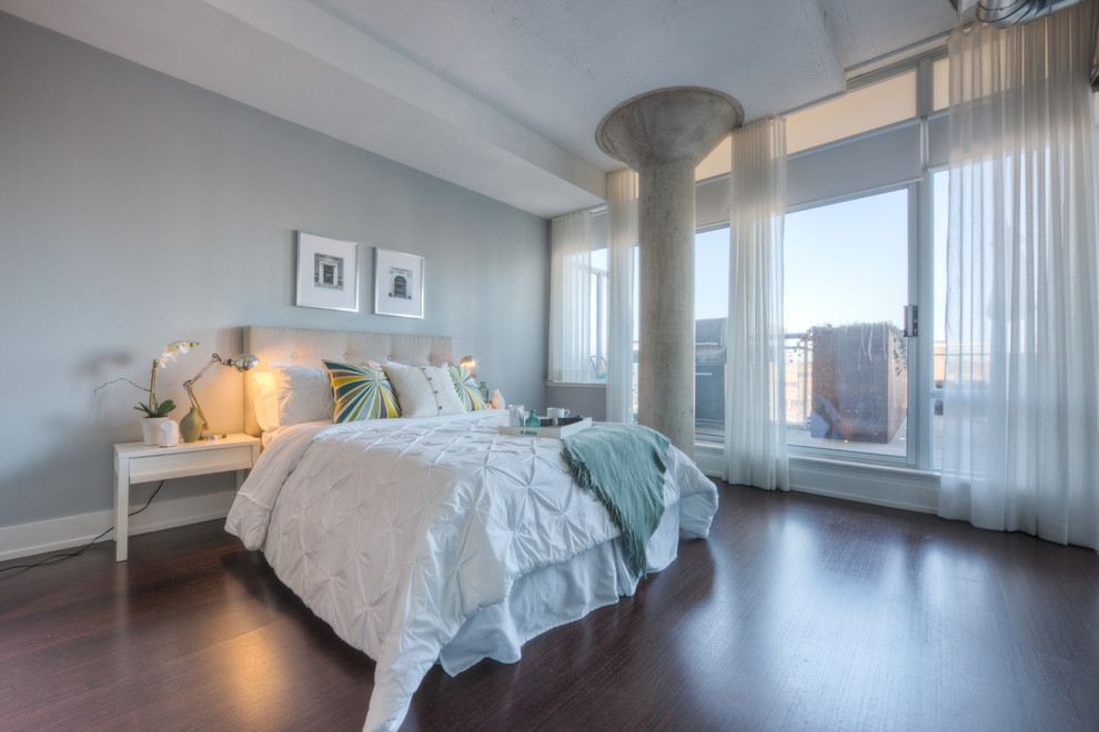 Modelo de dormitorio principal urbano de tamaño medio sin chimenea con paredes grises, suelo de madera en tonos medios y suelo marrón