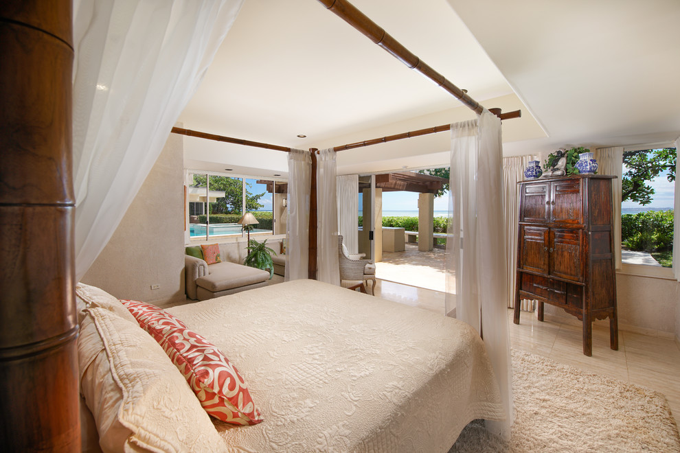 Modelo de habitación de invitados tropical de tamaño medio con paredes beige, suelo de travertino y suelo beige