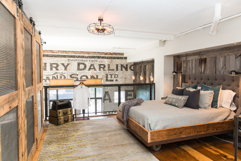 Immagine di una camera da letto stile loft industriale con pavimento in legno massello medio