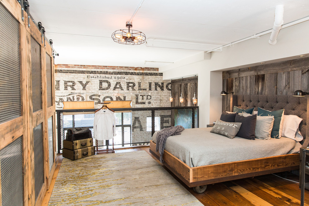 Urban loft-style medium tone wood floor bedroom photo in Vancouver