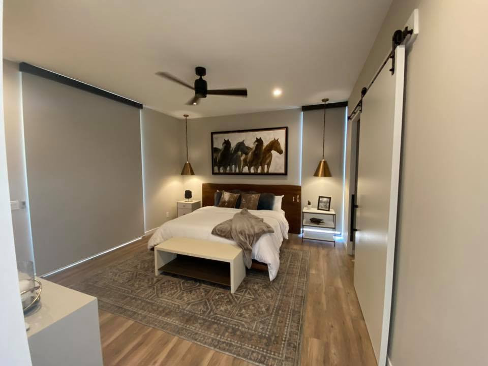 フェニックスにある広いサンタフェスタイルのおしゃれな主寝室 (グレーの壁、淡色無垢フローリング、茶色い床、折り上げ天井) のインテリア