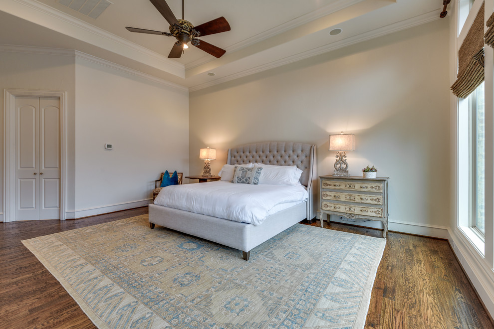 Imagen de dormitorio principal tradicional grande sin chimenea con paredes beige, suelo de madera en tonos medios y suelo marrón