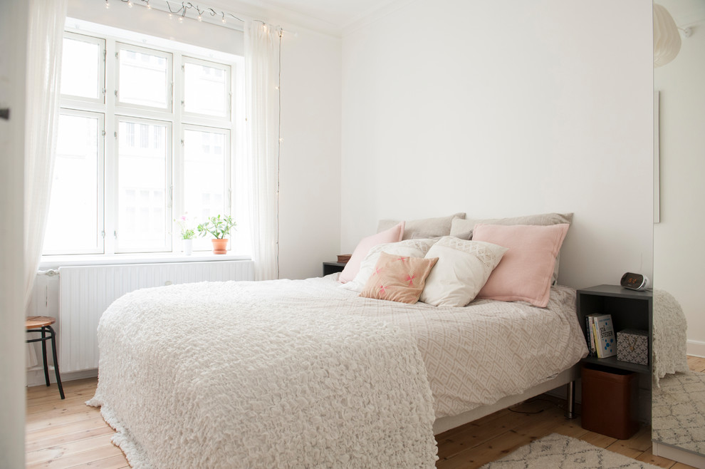 Foto de dormitorio principal nórdico con paredes blancas, suelo de madera en tonos medios y suelo marrón