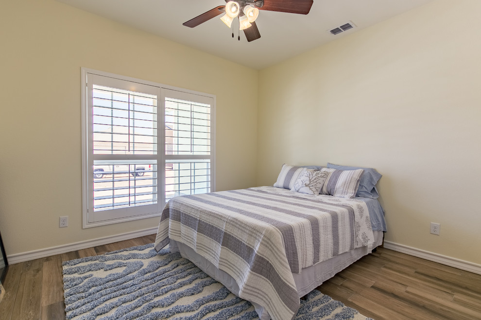 Ejemplo de habitación de invitados costera de tamaño medio sin chimenea con paredes amarillas y suelo de madera clara
