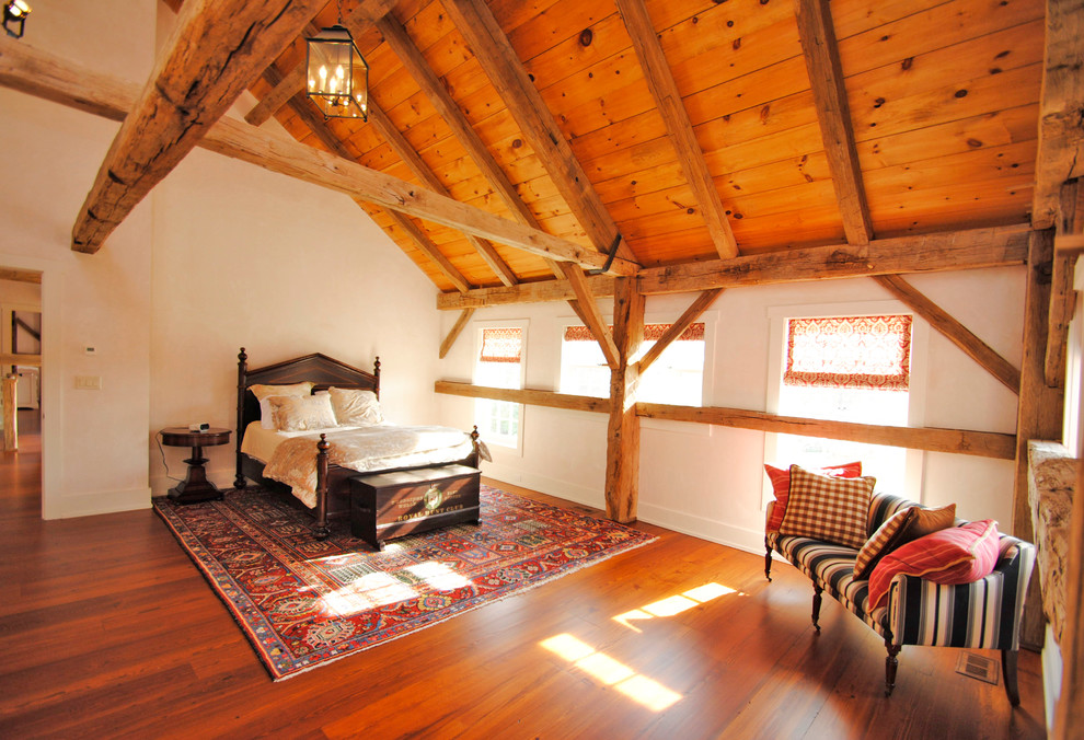 Modelo de dormitorio principal campestre grande sin chimenea con paredes beige y suelo de madera en tonos medios
