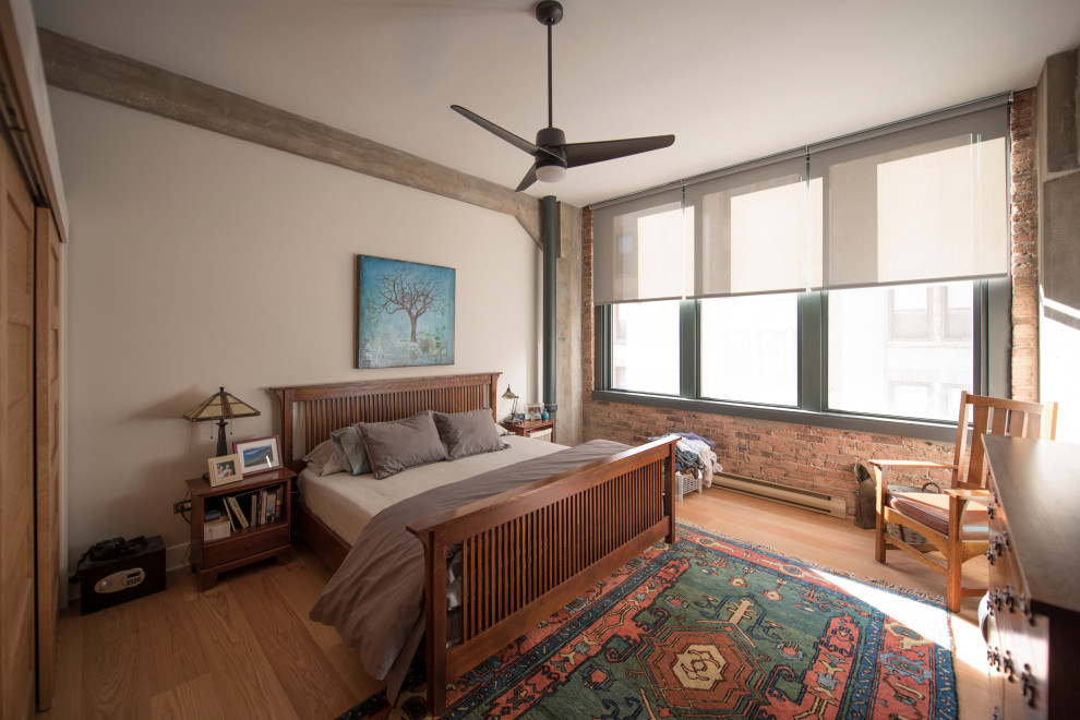 Imagen de dormitorio industrial con paredes blancas, suelo de madera clara y suelo beige