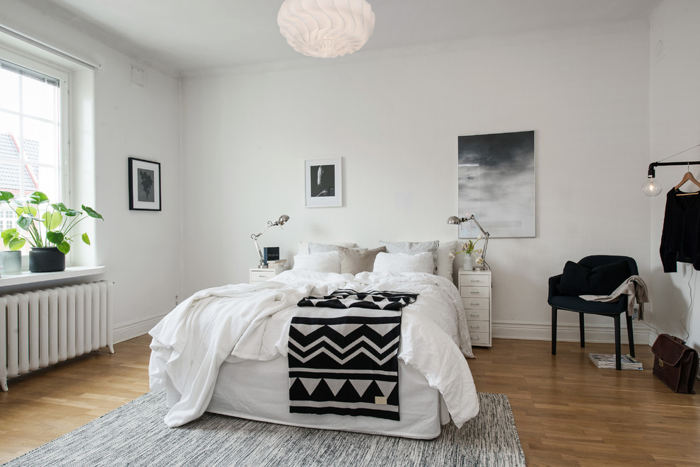 This is an example of a scandinavian bedroom in Gothenburg with white walls and medium hardwood flooring.
