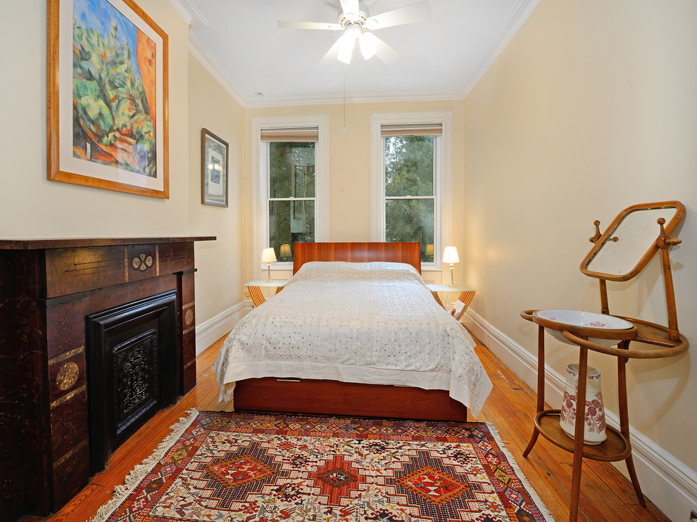 Exemple d'une chambre parentale tendance avec un sol en bois brun et une cheminée standard.