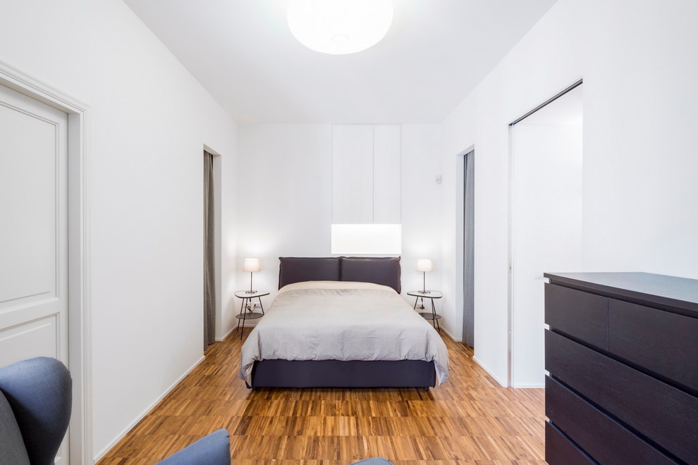 Imagen de dormitorio principal actual con paredes blancas y suelo de madera clara