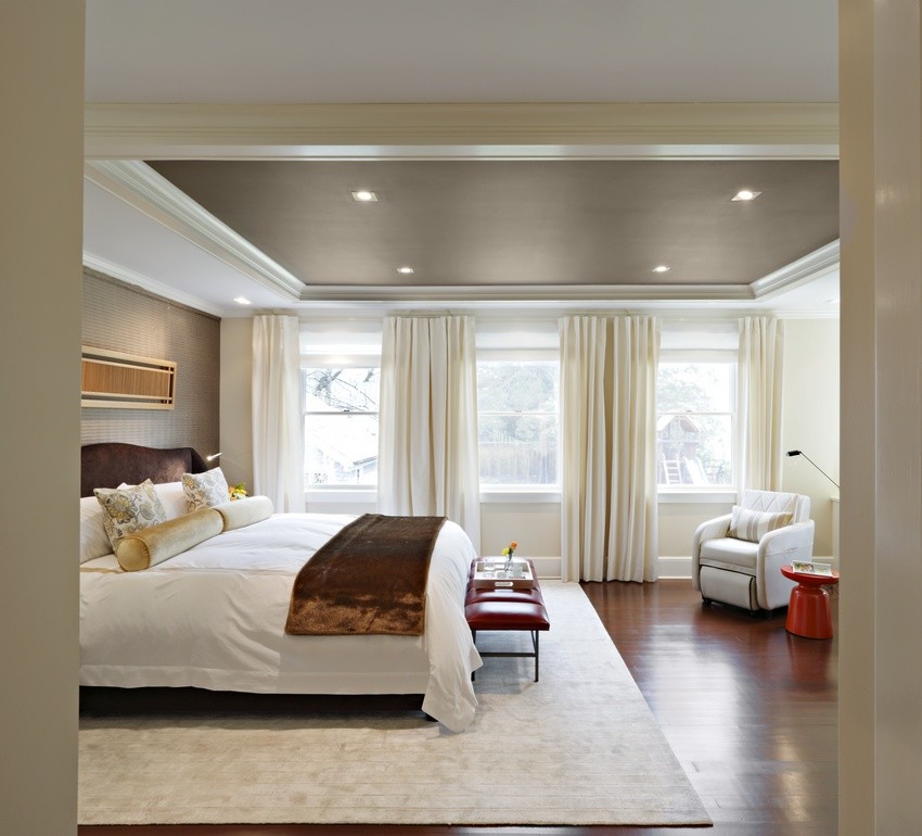 Свежая идея для дизайна: большая хозяйская спальня в стиле неоклассика (современная классика) с бежевыми стенами, светлым паркетным полом, стандартным камином, фасадом камина из дерева, коричневым полом и кессонным потолком - отличное фото интерьера
