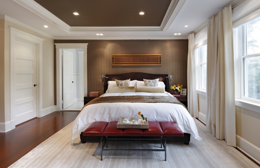 Großes Klassisches Hauptschlafzimmer mit beiger Wandfarbe, hellem Holzboden, Kamin, Kaminumrandung aus Holz, braunem Boden und Kassettendecke in New York