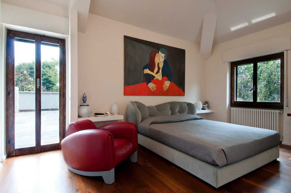 Großes Modernes Hauptschlafzimmer mit weißer Wandfarbe und dunklem Holzboden in Mailand