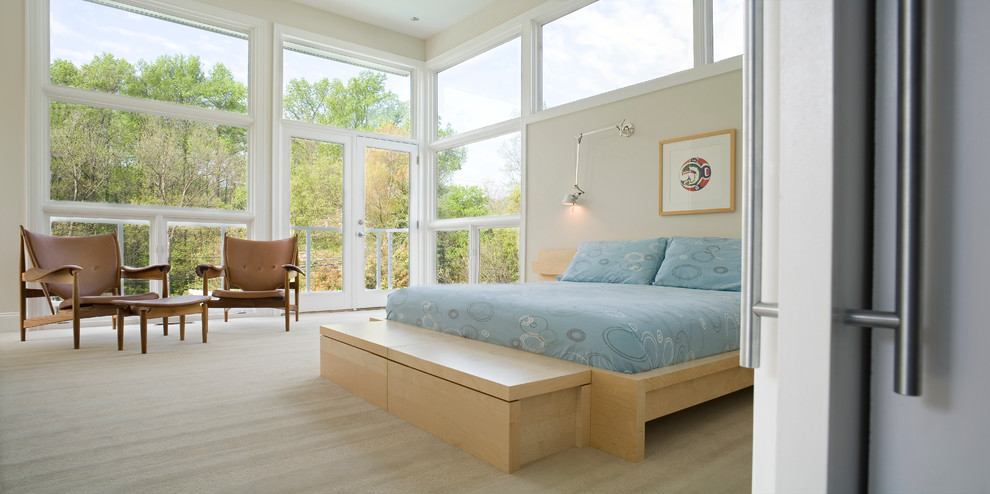 Immagine di una camera da letto contemporanea con pareti beige e parquet chiaro